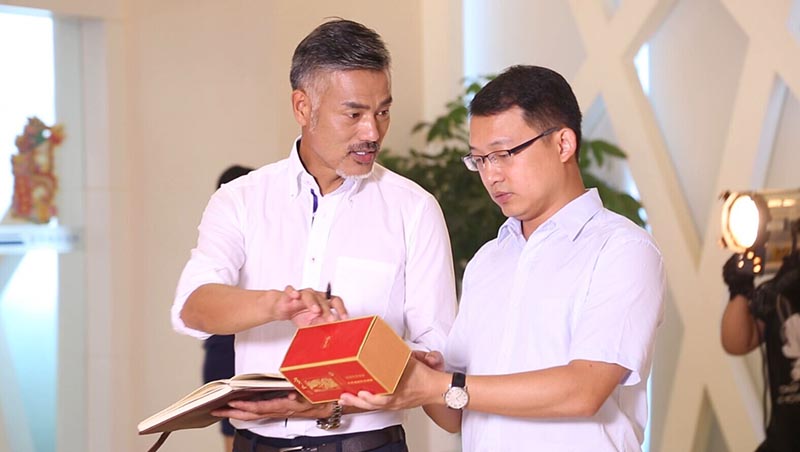 貴聯(lián)工作人員對演員詳細介紹煙盒包裝工藝流程